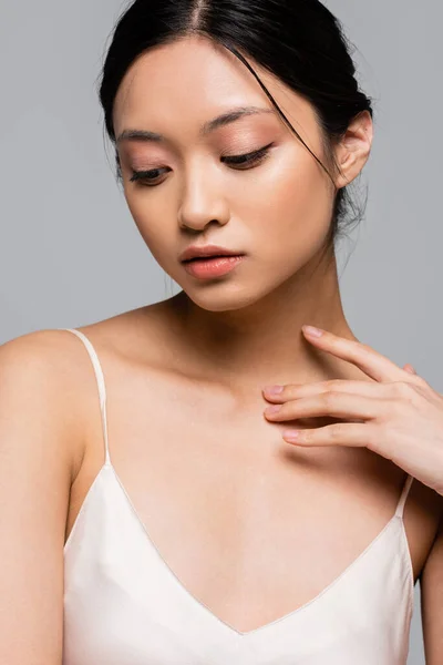 Азійська жінка з ідеальною шкірою торкається грудей ізольованих на сірому — стокове фото