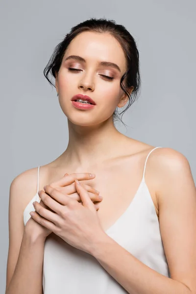 Mujer bonita en vestido de satén cerrando los ojos aislados en gris - foto de stock