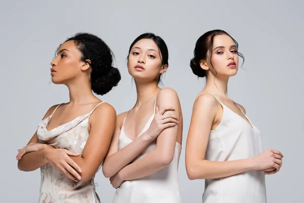 Mujeres jóvenes multiétnicas con la piel perfecta mirando a la cámara aislada en gris - foto de stock