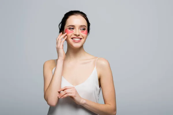 Mujer bonita en parches para los ojos de pie aislado en gris - foto de stock