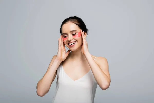 Happy woman in satin dress and eye patches smiling isolated on grey — Stock Photo