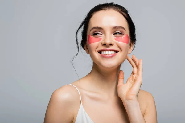 Mujer morena bonita con parches en los ojos de pie aislado en gris - foto de stock