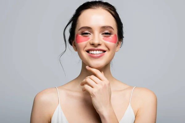 Happy young woman in eye patches looking at camera isolated on grey — Stock Photo