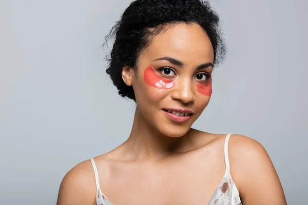 Jolie femme afro-américaine avec des patchs pour les yeux regardant la caméra isolée sur gris — Photo de stock