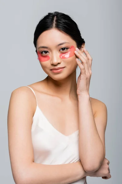 Junge asiatische Frau berührt Augenklappe isoliert auf grau — Stockfoto