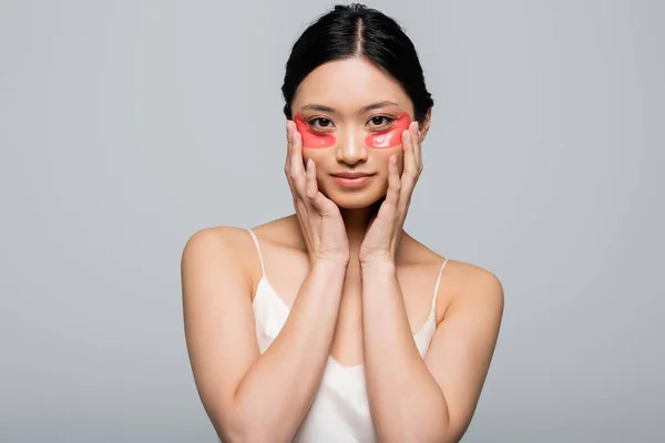Hübsche junge asiatische Frau mit Augenklappen, die in die Kamera schaut, isoliert auf grau — Stockfoto
