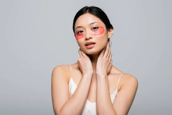 Asian woman in sating dress and eye patches looking at camera isolated on grey — Stock Photo