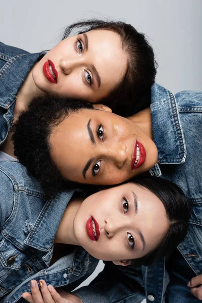 Jeunes femmes interracial avec lèvres rouges et fond de teint regardant caméra isolée sur gris — Photo de stock