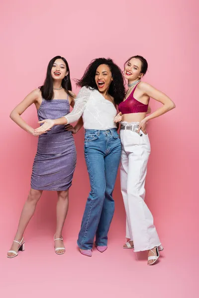 Mulheres multiétnicas na moda olhando para a câmera no fundo rosa — Fotografia de Stock