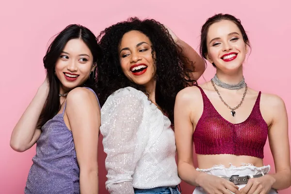 Glückliche multiethnische Frauen stehen während einer Party isoliert auf rosa — Stockfoto
