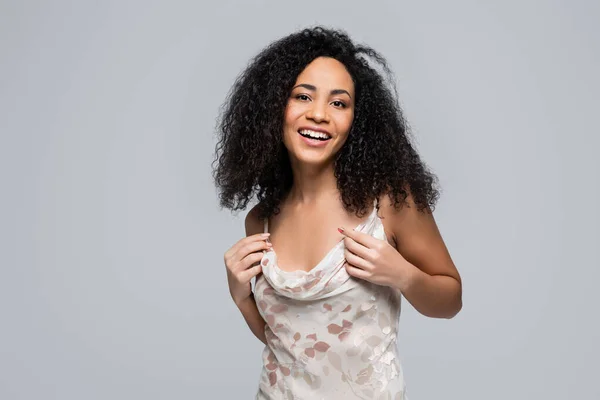 Feliz mujer afroamericana en vestido mirando a la cámara aislada en gris - foto de stock