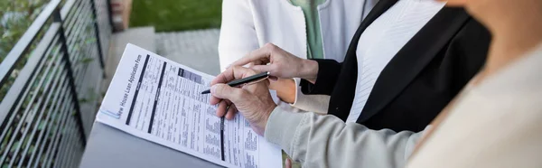 Cropped view of blurred man signing loan application near wife and realtor, banner — Stock Photo