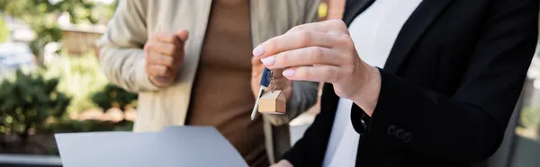 Teilansicht des Maklers, der Schlüssel in der Nähe des verschwommenen Mannes hält, Banner — Stockfoto