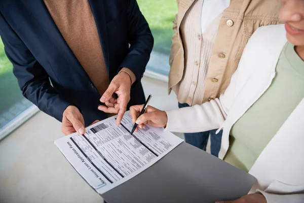 Vue recadrée de femme afro-américaine signant contrat près de l'agent immobilier et petite amie — Photo de stock