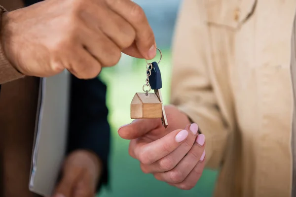 Vista recortada de agente inmobiliario dando clave a la mujer dentro de la nueva casa - foto de stock