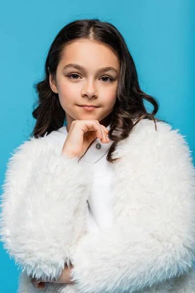 Preteen girl in white faux fur jacket looking at camera isolated on blue — Stock Photo