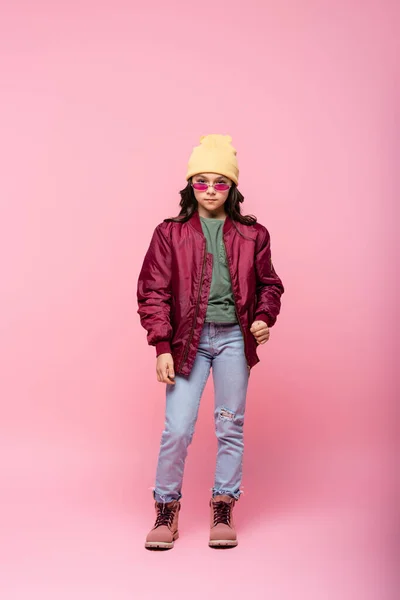 Full length of stylish preteen girl in trendy outfit and sunglasses on pink — Stock Photo