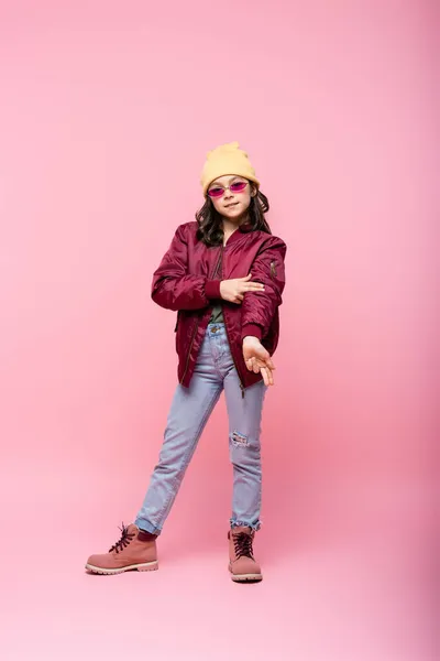 Full length of stylish preteen girl in trendy outfit posing on pink — Stock Photo