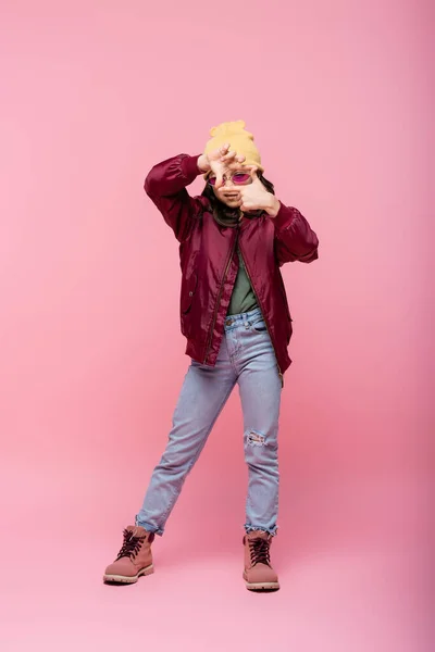 Full length of stylish preteen girl in trendy outfit making frame hands gesture on pink — Stock Photo