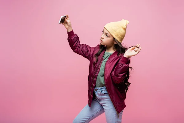Preteen girl in stylish outfit taking selfie isolated on pink — Stock Photo