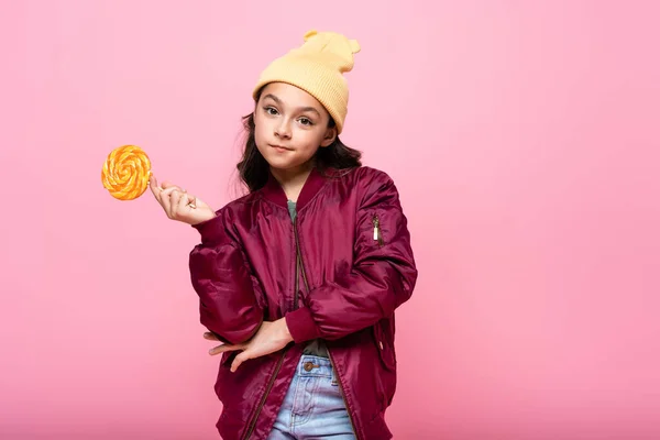 Stylish preteen kid in winter outfit holding lollipop isolated on pink — Stock Photo