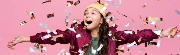 Excité fille préadolescente en tenue élégante souriant près de tomber confettis sur rose, bannière — Photo de stock