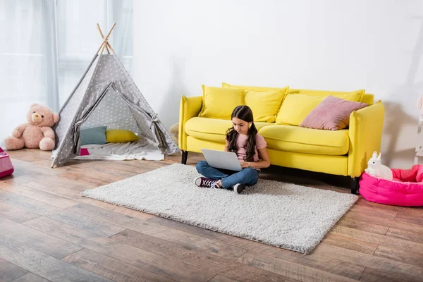 Frühchen sitzt auf Teppich und benutzt Laptop im modernen Wohnzimmer — Stockfoto