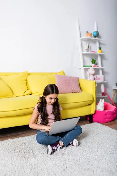 Frühchen sitzt auf Teppich und benutzt Laptop im modernen Wohnzimmer — Stockfoto