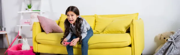 QUIIV, UCRÂNIA - SETEMBRO 17, 2021: menina pré-adolescente gritando enquanto joga videogame em casa, banner — Fotografia de Stock