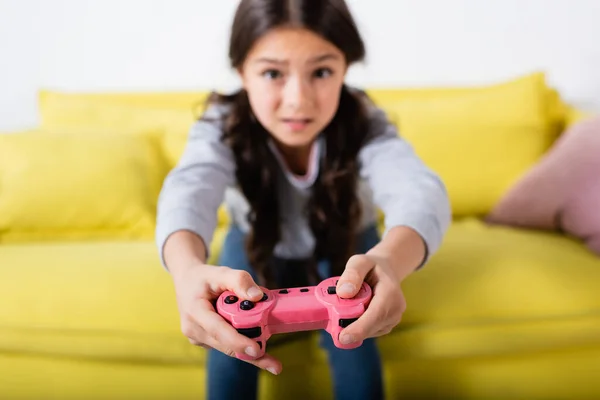 KYIV, UKRAINE - SEPTEMBER 17, 2021: blurred and worried preteen girl playing video game at home — Stock Photo