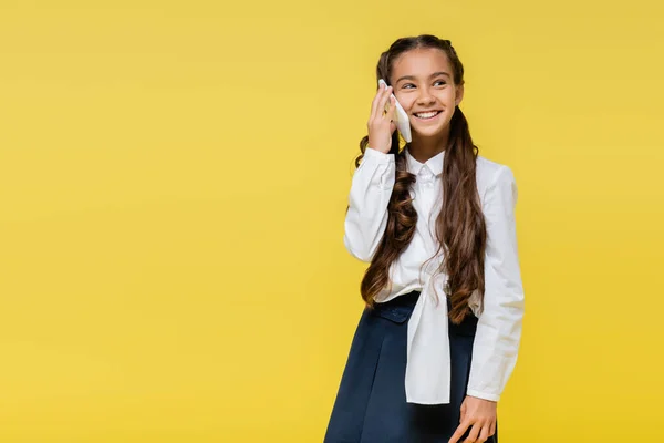 Écolier souriant parlant sur téléphone mobile sur fond jaune avec espace de copie — Photo de stock