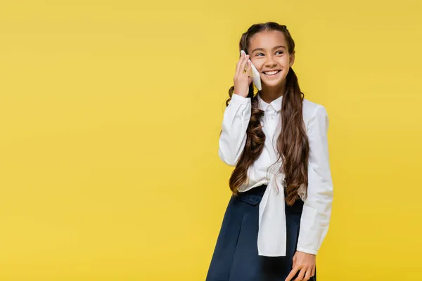 Estudante sorrindo falando no celular em fundo amarelo com espaço de cópia — Fotografia de Stock