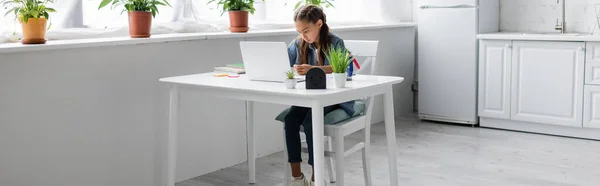 Kind benutzt Laptop bei Schularbeiten in Küche, Banner — Stockfoto