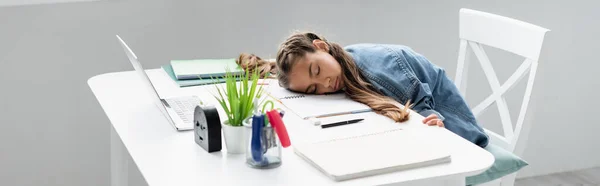 Child sleeping near notebooks and laptop on table at home, banner — Stock Photo