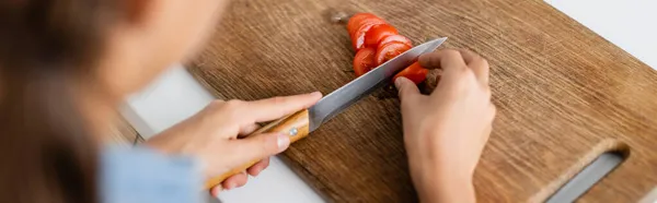 Vista recortada del niño cortando tomate cherry en pancarta de cocina - foto de stock
