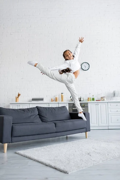 Счастливый дошкольник прыгнул с дивана на кухне — стоковое фото