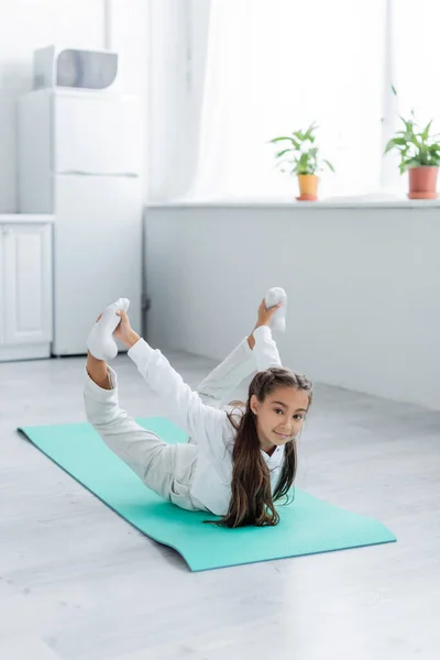 Preteen girl in sportswear training on fitness mat at home — Stock Photo