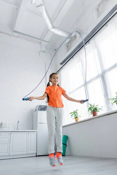 Low angle view of preteen kid training with jump rope at home — Stock Photo