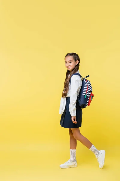 Alumno preadolescente con mochila sonriendo a la cámara sobre fondo amarillo - foto de stock