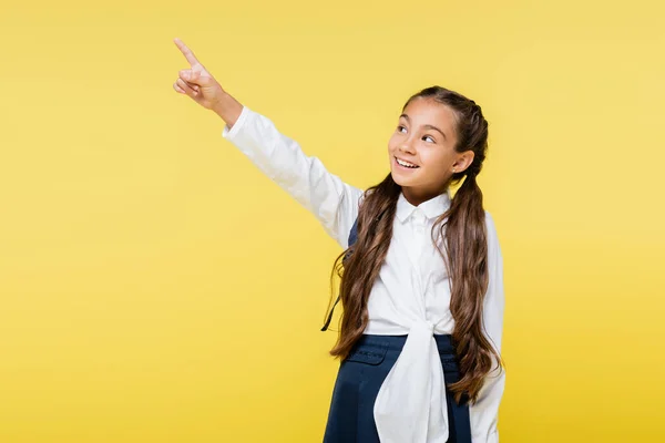 Happy pupil in shirt pointing with finger isolated on yellow — Stock Photo