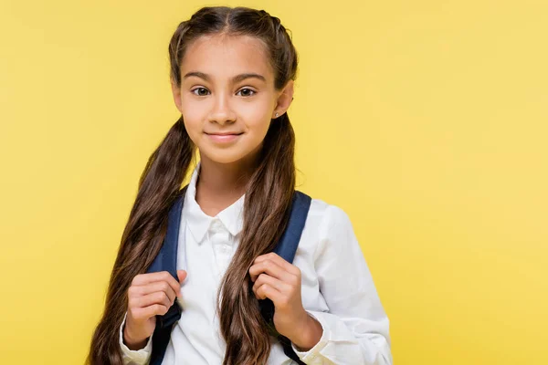 Preteen girl in shirt holding backpack and looking at camera isolated on yellow — Stock Photo