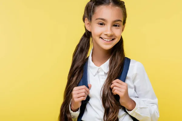 Happy kid in shirt holding backpack and looking at camera isolated on yellow — Stock Photo