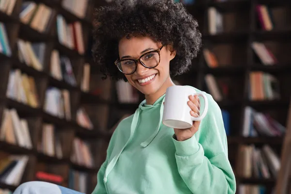 Allegra donna afro-americana in occhiali con in mano una tazza di caffè — Foto stock