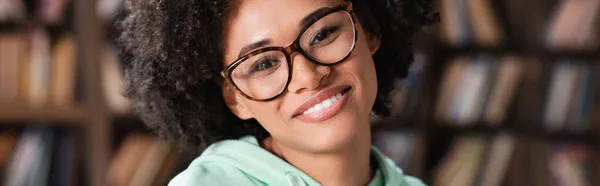 Cheerful african american woman in eyeglasses looking at camera, banner — Stock Photo