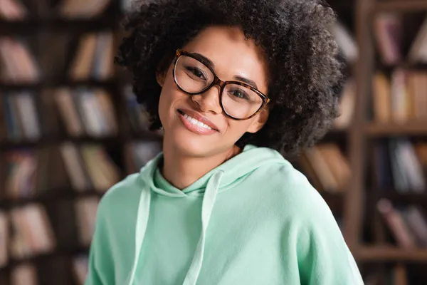 Joyeuse femme afro-américaine en lunettes regardant la caméra — Photo de stock