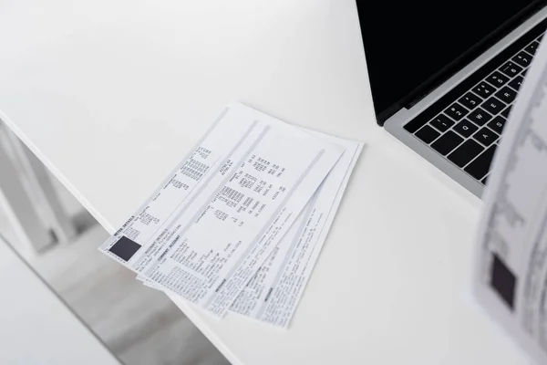 Bills near laptop with blank screen on table at home — Stock Photo