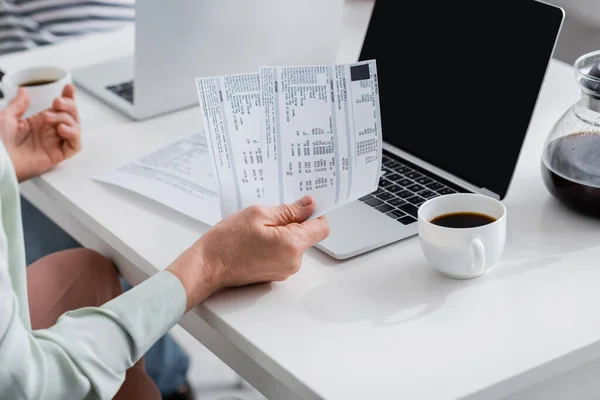 Ausgeschnittene Ansicht einer Frau mit Geldscheinen in der Nähe von Kaffee und Laptop zu Hause — Stockfoto