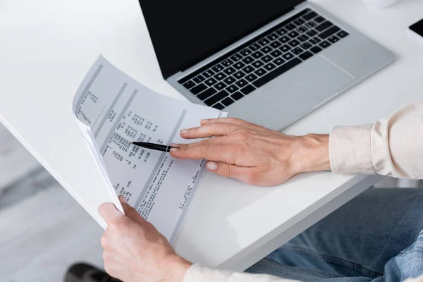 Ausgeschnittene Ansicht einer Frau, die in der Nähe ihres Laptops zu Hause Rechnungen zählt — Stockfoto