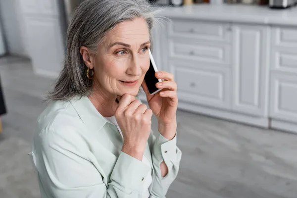 Smiling mature woman talking on mobile phone at home — Stock Photo
