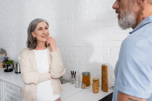 Middle aged woman looking at blurred husband at home — Stock Photo